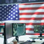 Dead Paychecks Busted — $99M Halted A command center with multiple computer monitors and an American flag in the background