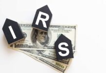 Audit Dollars VANISH From IRS – DETAILS Blocks spelling 'IRS' placed on top of hundred dollar bills featuring Benjamin Franklin