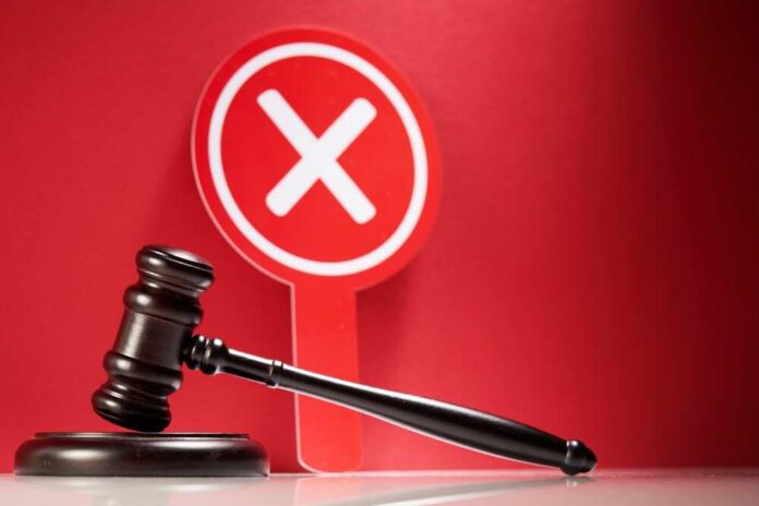 Wooden,Gavel,And,Cross,Mark,On,Red,Background. Judge's gavel with red cross sign in background