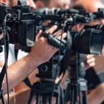 CHAOS in Lib City: Officers Run Down! television cameras on tripods at a media event