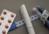 Fast-Food Flip: GLP-1 Changes Everything Medication blister pack, insulin pens, and tape measure on a gray surface