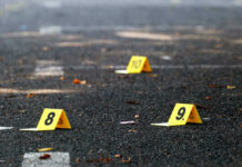 NY Times Exec Shot Dead – Shocking Details Yellow evidence markers labeled 8, 9, 10 on pavement.