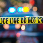 Buried Suitcase Murder Horror Stuns Cops Police tape and lights at crime scene.
