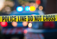 Buried Suitcase Murder Horror Stuns Cops Police tape and lights at crime scene.