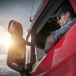 Truck driver looking out window at sunset.