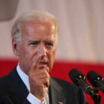Joe Biden speaking at a podium, pointing his finger during a speech