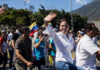 María Corina Machado waving in a street march alongside Teddy Williams
