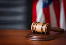 Ankle Monitor Cut, Trial Back On A wooden gavel resting on a sound block with an American flag in the background