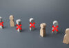 Wooden figures representing people with red crosses indicating exclusion