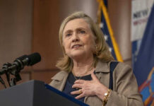 Hillary Clinton speaking at a podium with a microphone