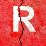 Cracked red wall with white letter R.