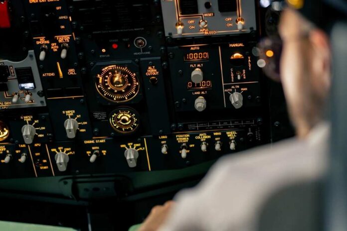 Airplane,Cabin,The,Pilot,Checks,The,Plane's,Electronics,By,Pressing Aircraft cockpit overhead panel with illuminated switches and gauges