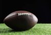American football on grass with black background