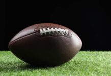 American football on grass with black background