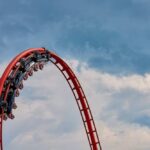 Red roller coaster loop against a cloudy sky