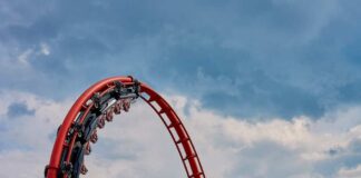 Red roller coaster loop against a cloudy sky