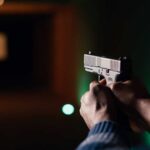 Hands aiming a pistol at an indoor shooting range