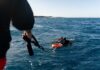 Two scuba divers in the ocean being assisted by a person holding a rescue line