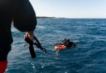 Big Expedition, Brutal Letdown Two scuba divers in the ocean being assisted by a person holding a rescue line