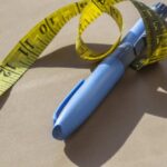 New Jab Melts Dangerous Fat Blue pen with yellow measuring tape on a table