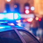 Police Probe Chilling Pattern Close-up of a police car with blue emergency lights in a city at night